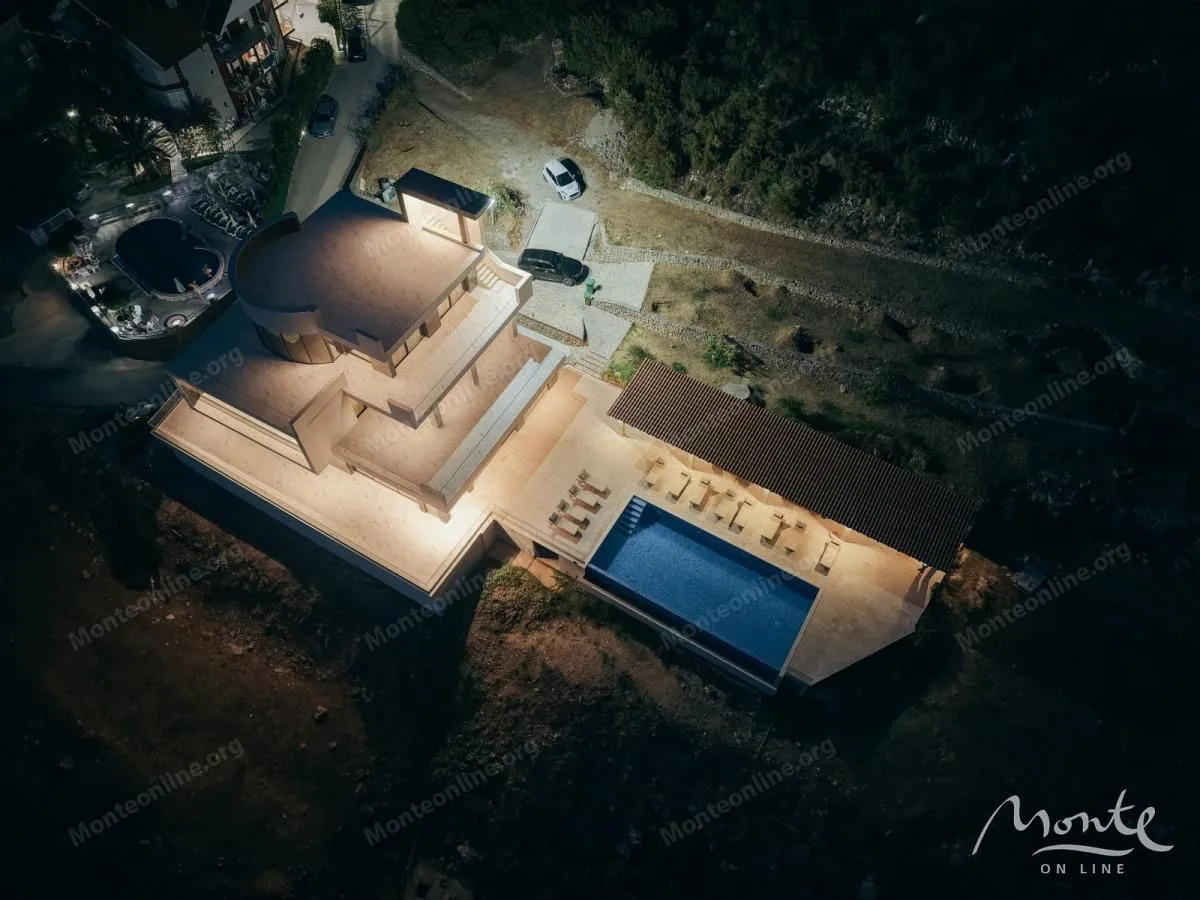 Night aerial view showing a modern villa with an illuminated swimming pool and terrace.