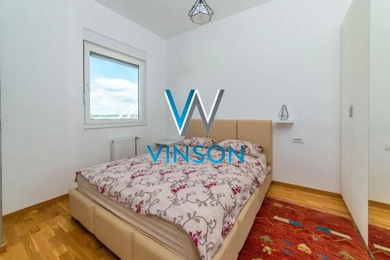 Bright bedroom with a double bed, window, and wardrobe.