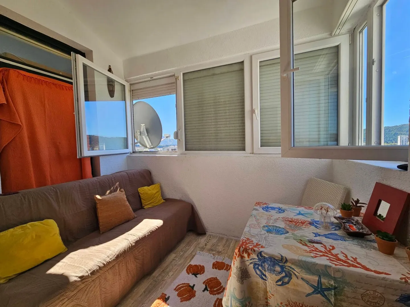 Enclosed balcony with a seating set and dining table.