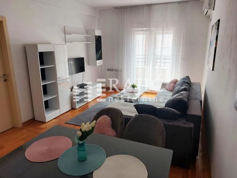Living room with sofa, TV unit, and dining table.