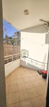 Covered balcony with tiled flooring and a view of surrounding trees. - image 8