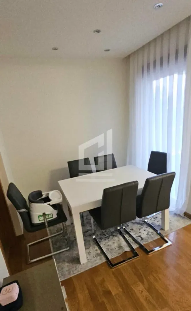 Dining area with a white table, dark chairs, and a high chair.