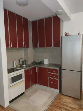 A small kitchen with red cabinets and a refrigerator. - image 3