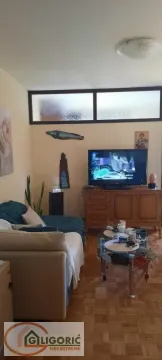 Nameštena dnevna soba sa garniturom, televizorom i drvenim stočićem. - image 5