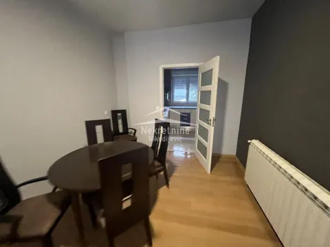 Dining area with a table and chairs, looking into the kitchen through an open door. - image 6