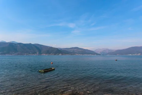 Pogled na more i planine u daljini sa malom barkom u vodi. - image 4