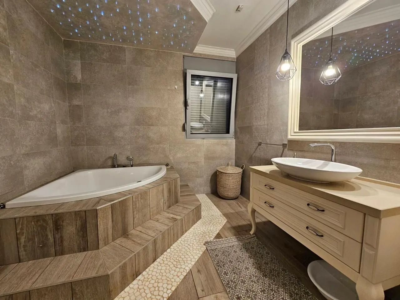 Modern bathroom with a corner bathtub and a washbasin.