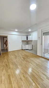 Living room with laminate flooring and a small corner kitchen. - image 3