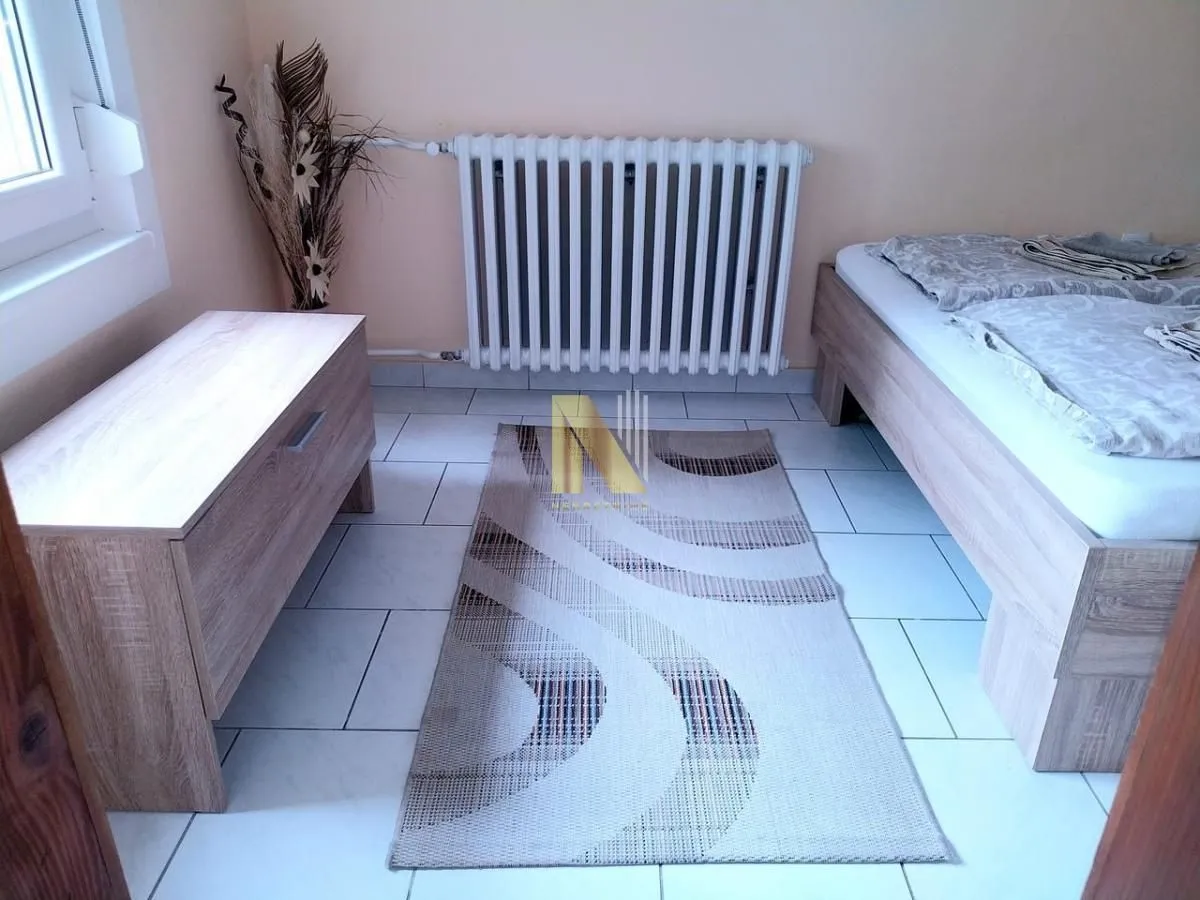 Spavaća soba sa krevetom, komodom i radijatorom.