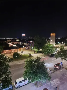 Night view from the window overlooking the illuminated street and surrounding buildings. - image 15