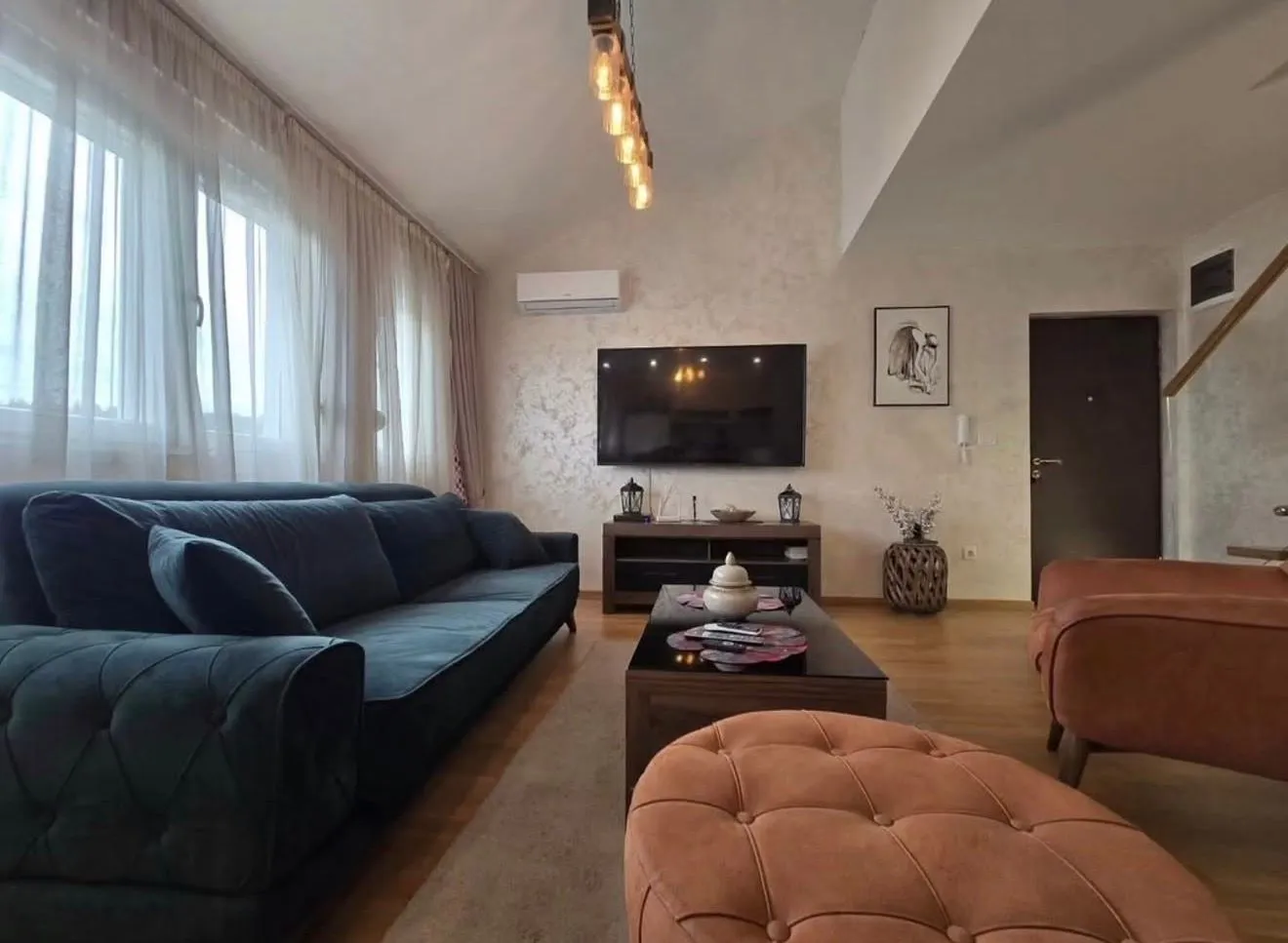 Spacious living room with a sofa set and a wall-mounted TV.