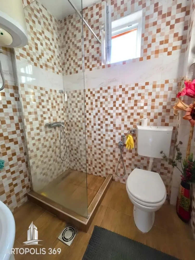 Kupatilo sa tuš kabinom i šarenim pločicama.