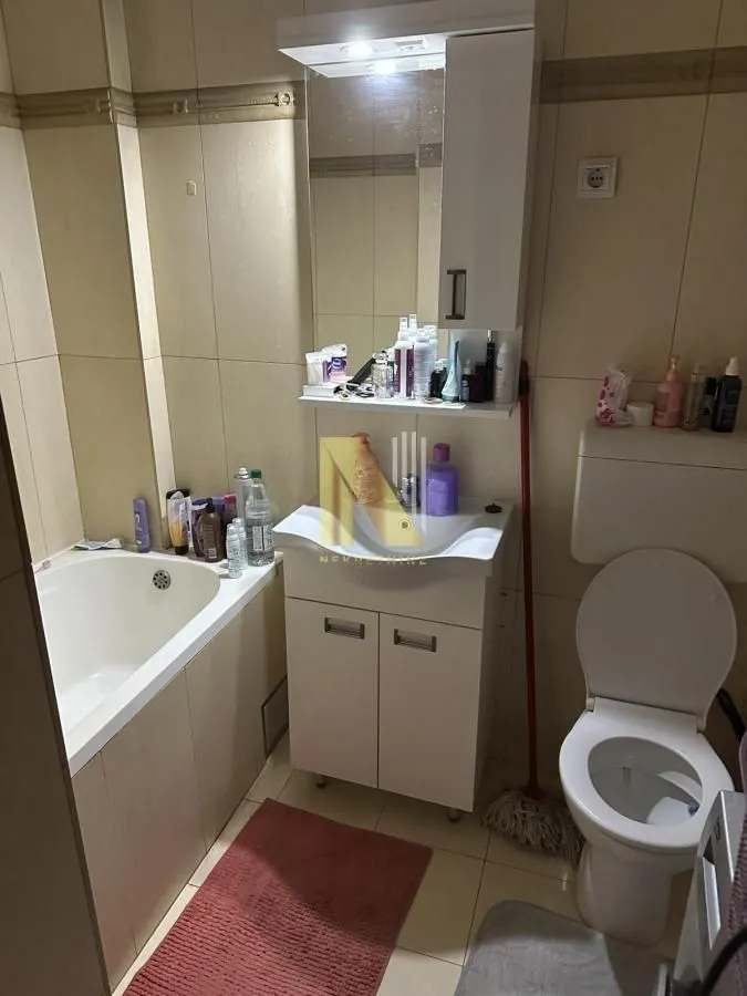 Kupatilo opremljeno kadom, umivaonikom sa ormarićem, ogledalom i toaletom.
