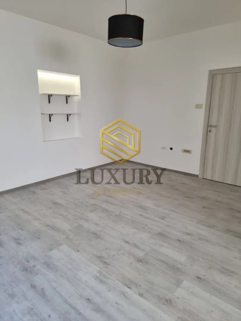 Empty room with laminate flooring, white walls, and built-in shelves.
