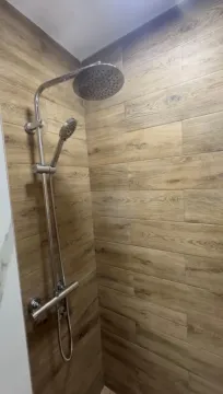 Shower cabin with wood-effect tiles and a modern faucet. - image 9