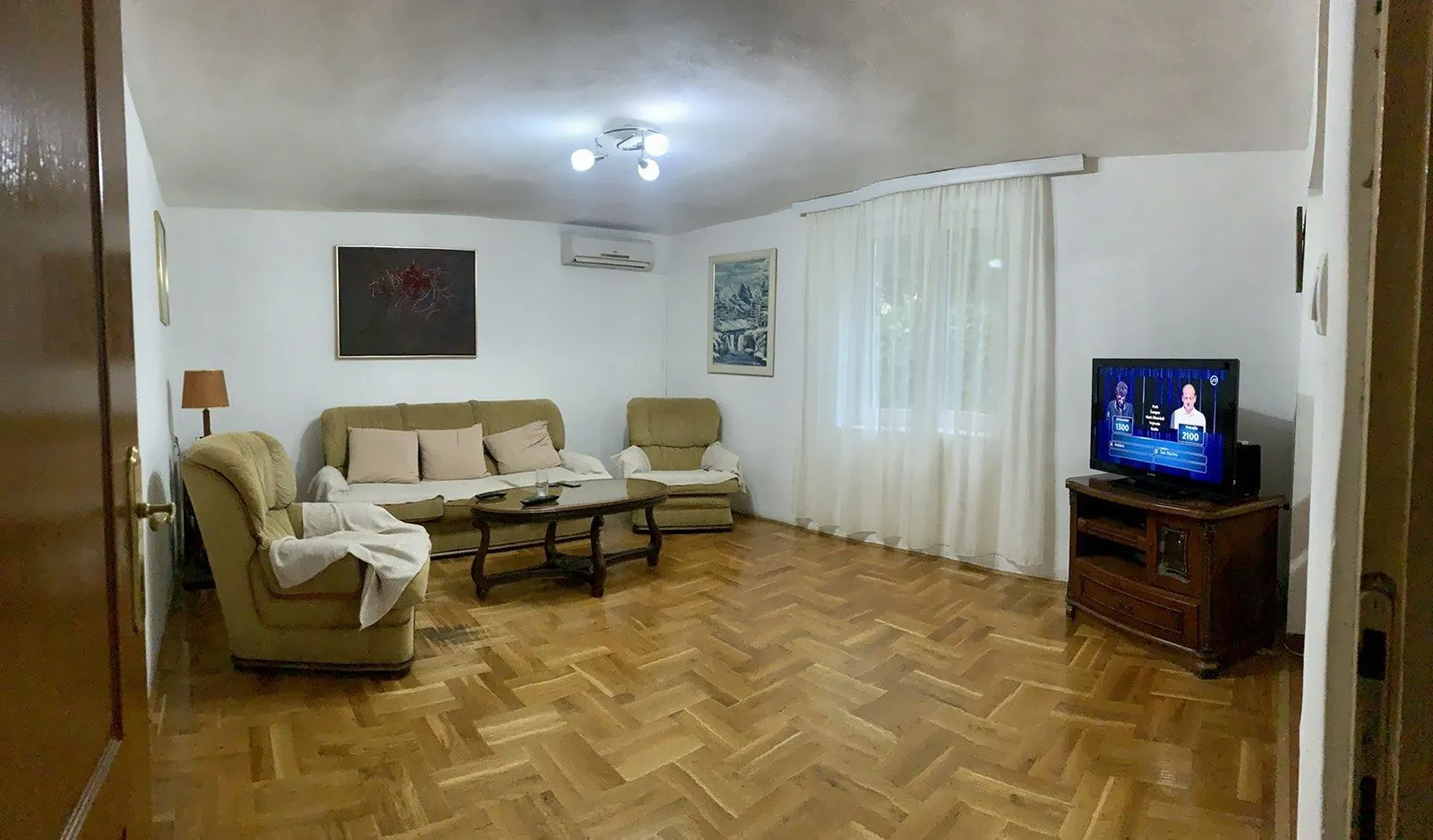 Living room with a seating set, television, and parquet flooring.