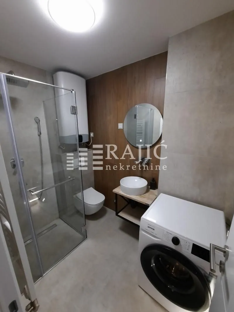 Modernly equipped bathroom with a walk-in shower and washing machine.