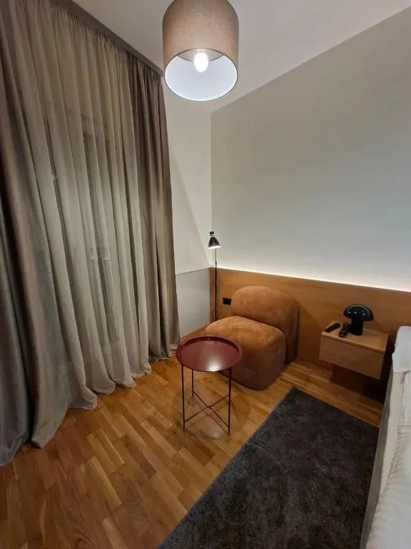 Modern bedroom with a double bed, armchair, and hardwood flooring.