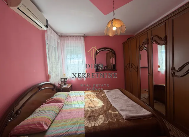 Furnished bedroom with a large double bed and a wooden wardrobe.
