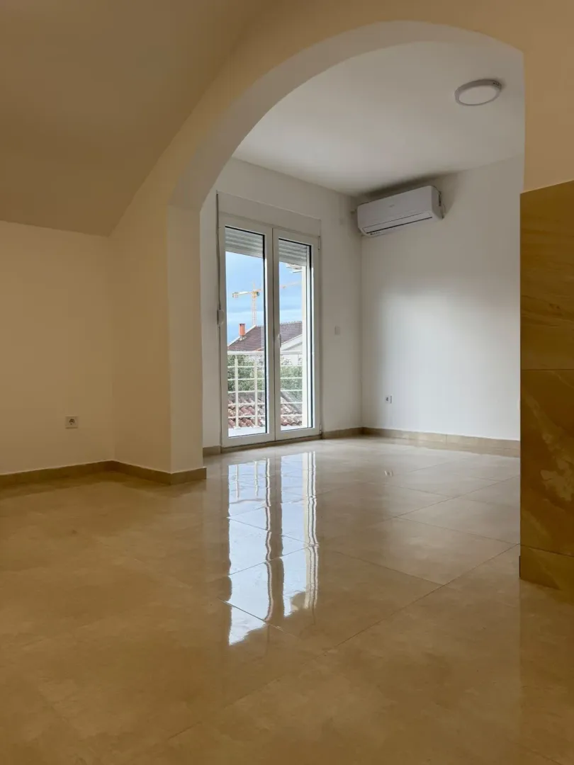 Empty room with ceramic tiles and balcony doors.