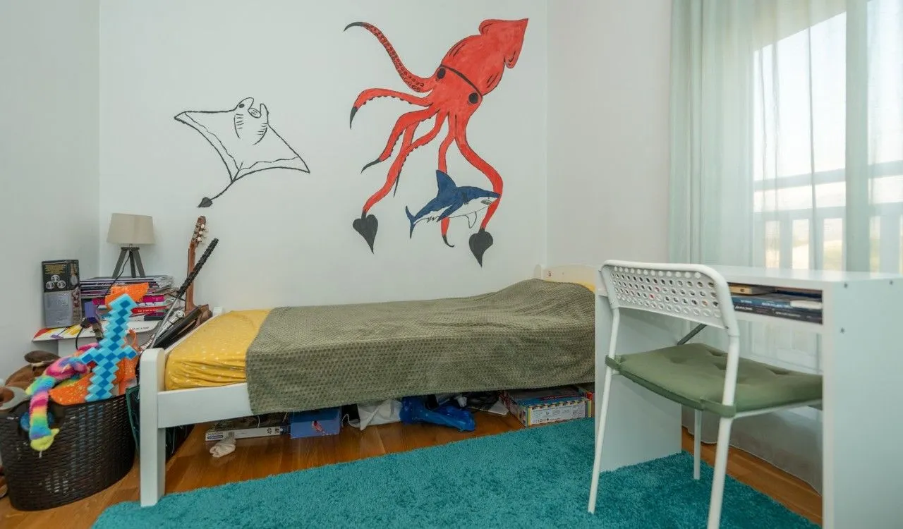 Children's bedroom with a bed, desk, and wall drawings.