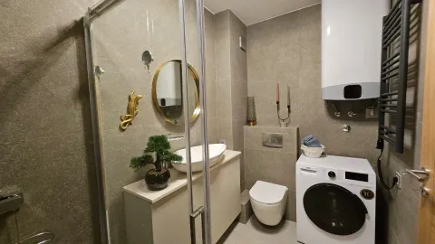 Moderno kupatilo sa tuš kabinom, veš mašinom i zlatnim detaljima. - image 5