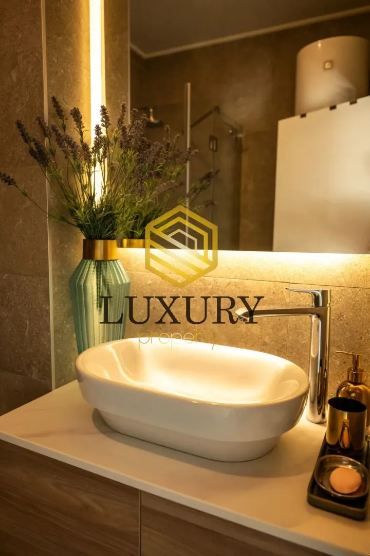 Modernly equipped bathroom with a washbasin and illuminated mirror.