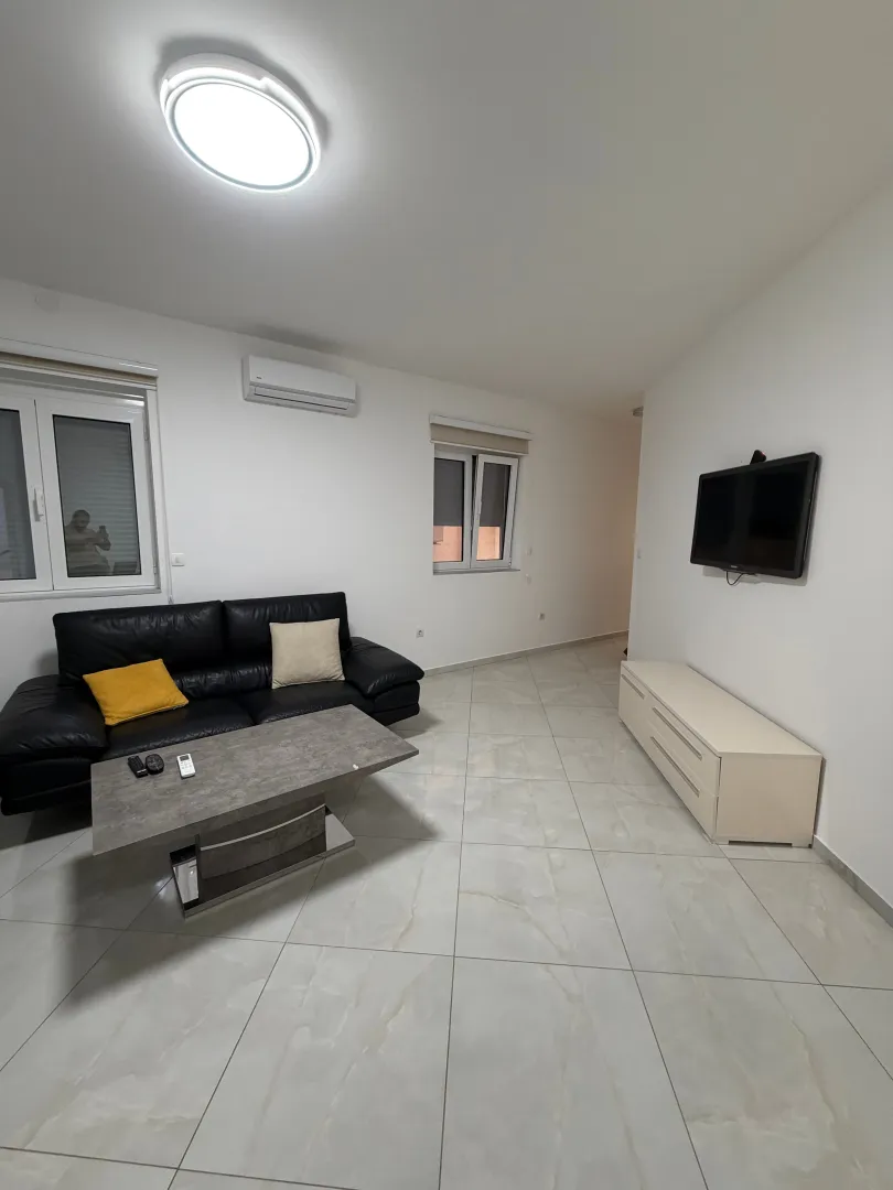 Living room with a black leather sofa, coffee table, and a wall-mounted TV.