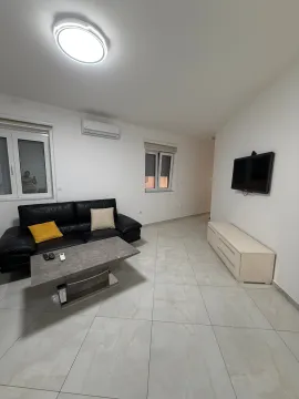 Living room with a black leather sofa, coffee table, and a wall-mounted TV. - image 2
