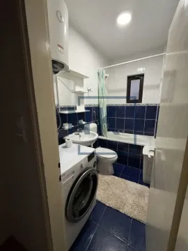 Small bathroom with blue tiles, bathtub, washbasin, washing machine, and water heater. - image 2