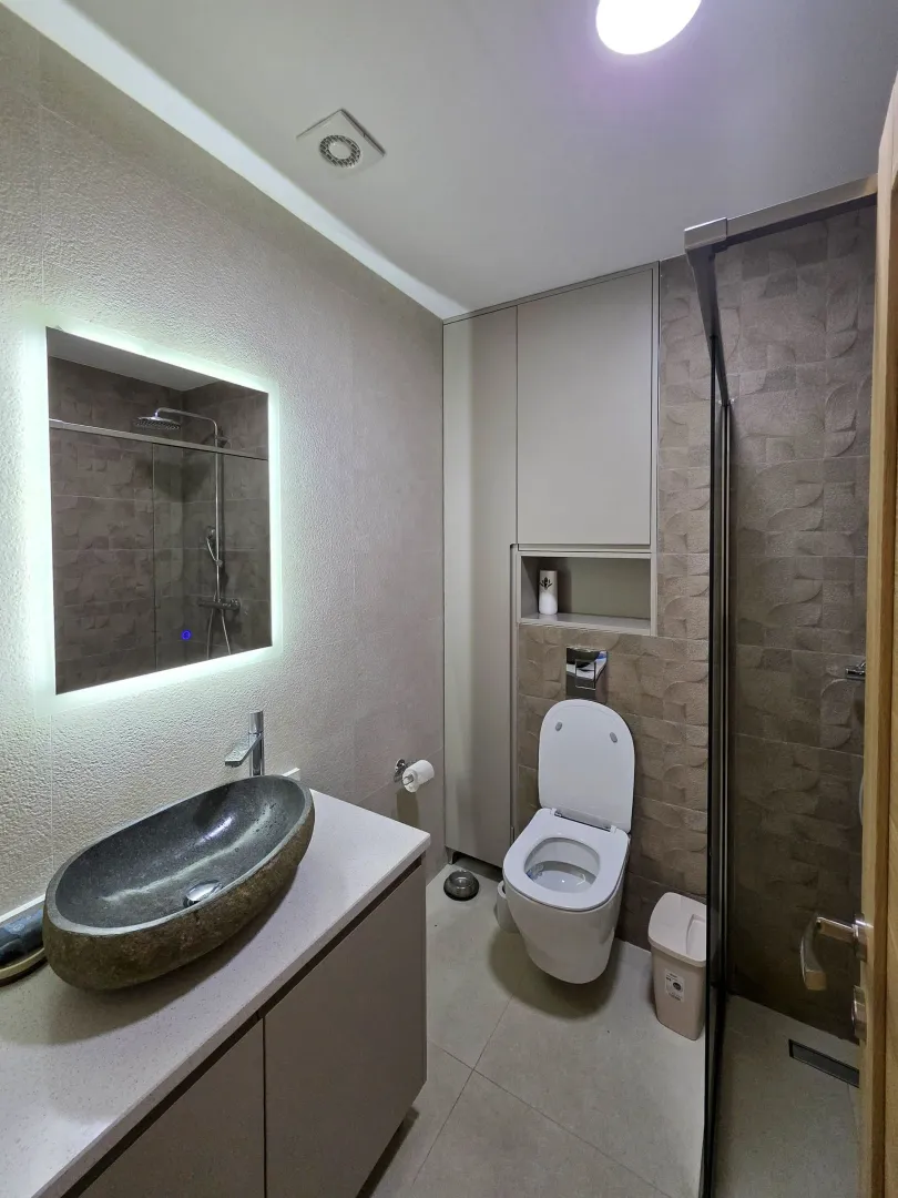 Moderne kupatilo sa umivaonikom od kamena, wc šoljom i tuš kabinom.