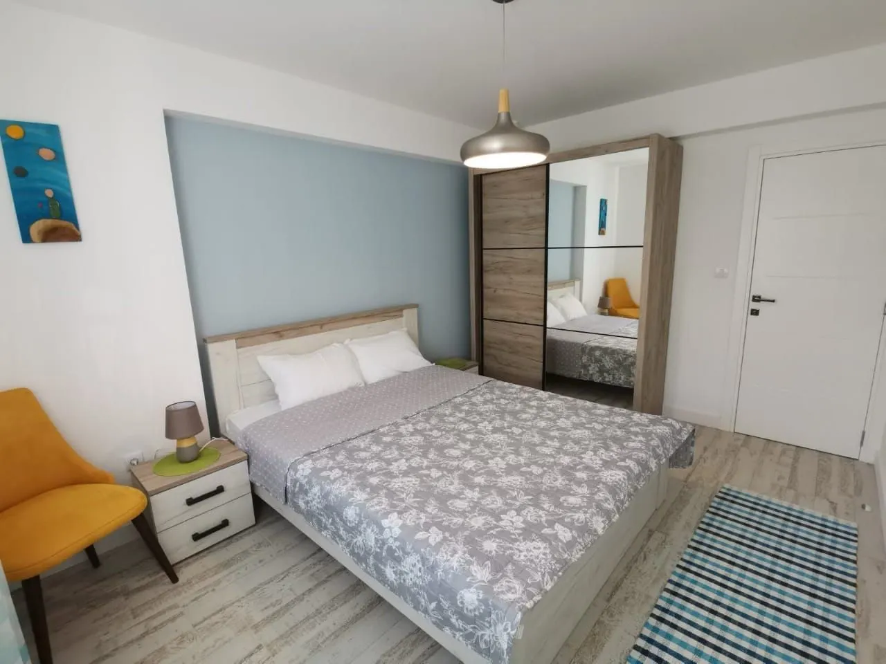 Furnished bedroom with a double bed, wardrobe, and yellow armchair.