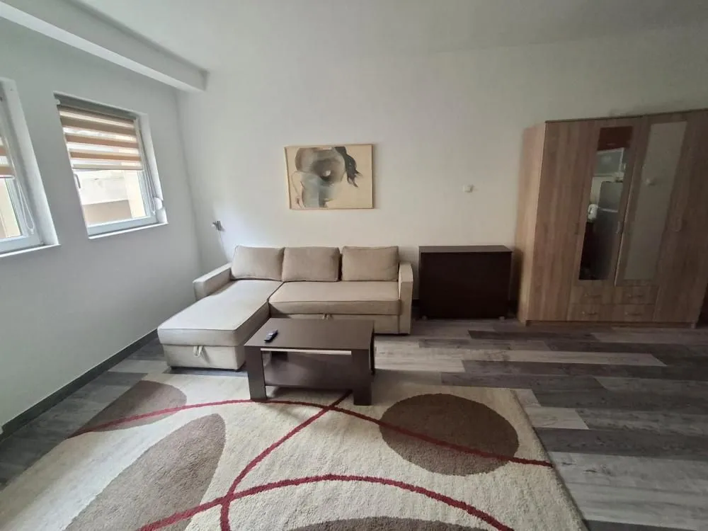 Living room with a sectional sofa, coffee table, wardrobe, and windows.