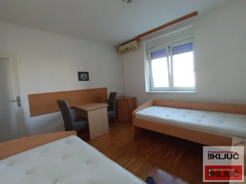 Spavaća soba sa dva kreveta, radnim stolom i prozorom. - image 11