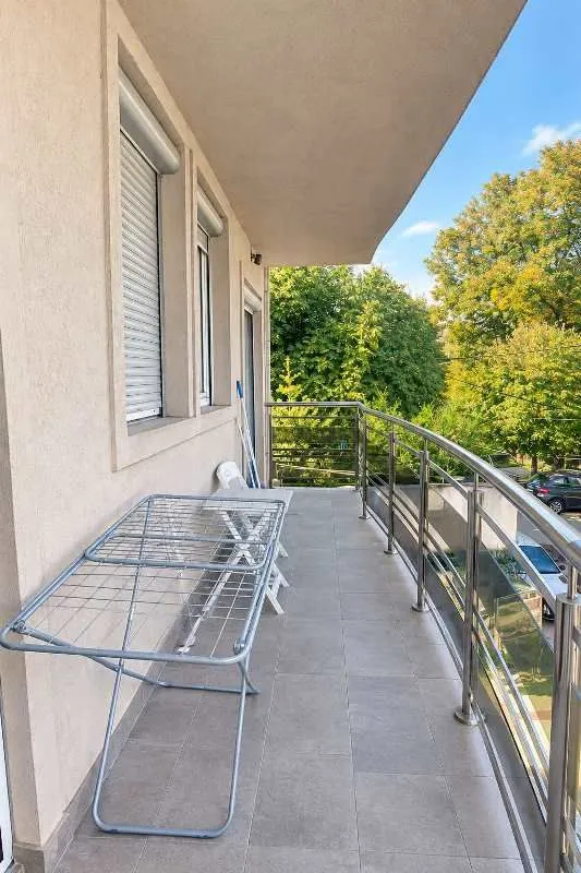 Spacious tiled balcony with metal railing and a clothes drying rack.