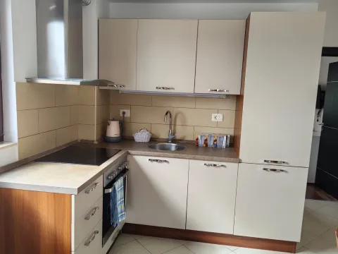 Small kitchen with beige cabinetry, built-in cooktop, and sink. - image 5