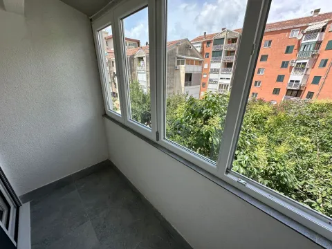Zastakljena terasa sa pogledom na okolne zgrade i zelenilo. - image 15