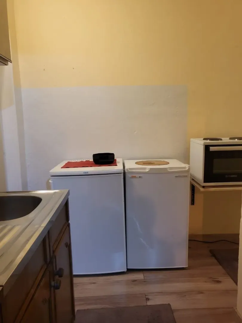 Jednostavan kuhinjski ugao sa dva mini frižidera i malim šporetom.