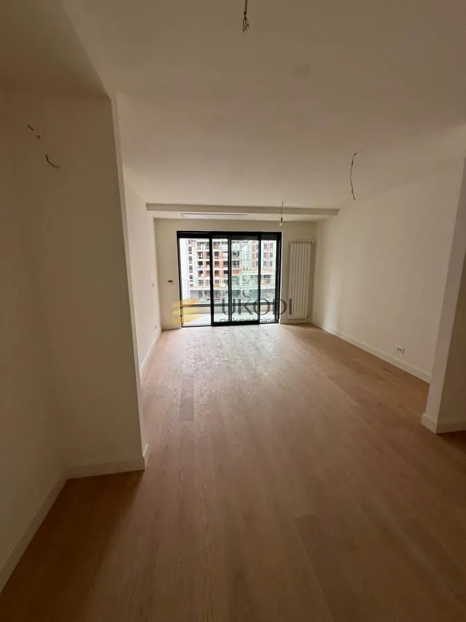 Prazna soba sa drvenim podom i izlazom na terasu.
