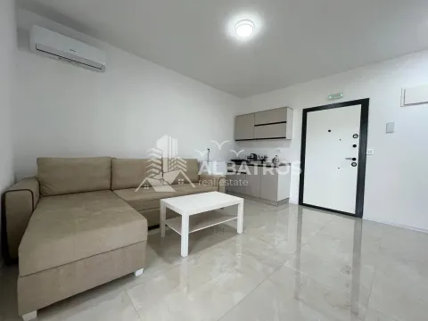 Living room with a sectional sofa, coffee table, and a small kitchenette in the background. - image 3