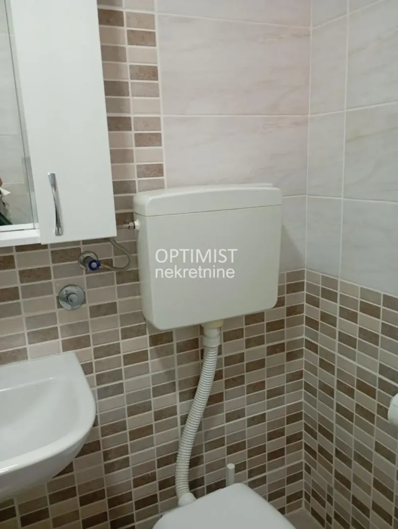 Pogled na deo kupatila sa umivaonikom, WC šoljom i zidnim pločicama.
