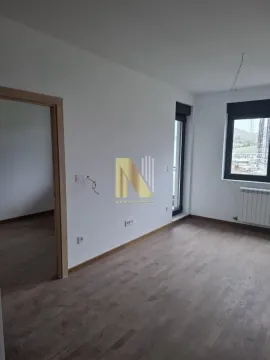 Prazna soba sa drvenim podom i vodenim žigom agencije na zidu. - image 5