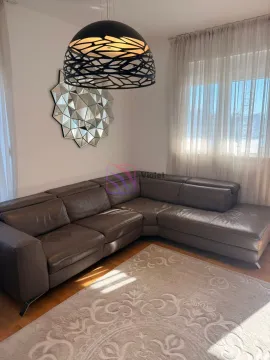 Udobna dnevna soba sa velikom kožnom garniturom i ukrasnim ogledalom na zidu. - image 2