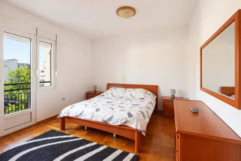 Spavaća soba sa bračnim krevetom, drvenim namještajem i izlazom na terasu. - image 5