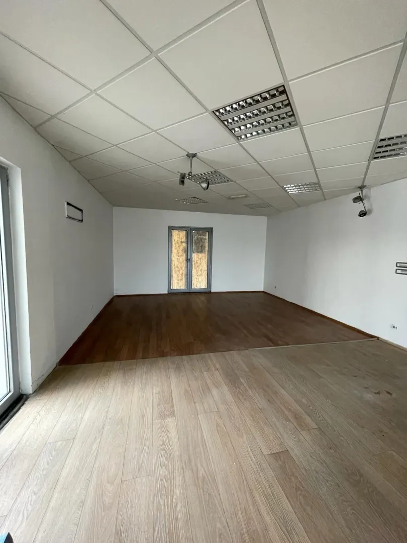 Prazna prostrana prostorija sa laminatom i spuštenim plafonom.