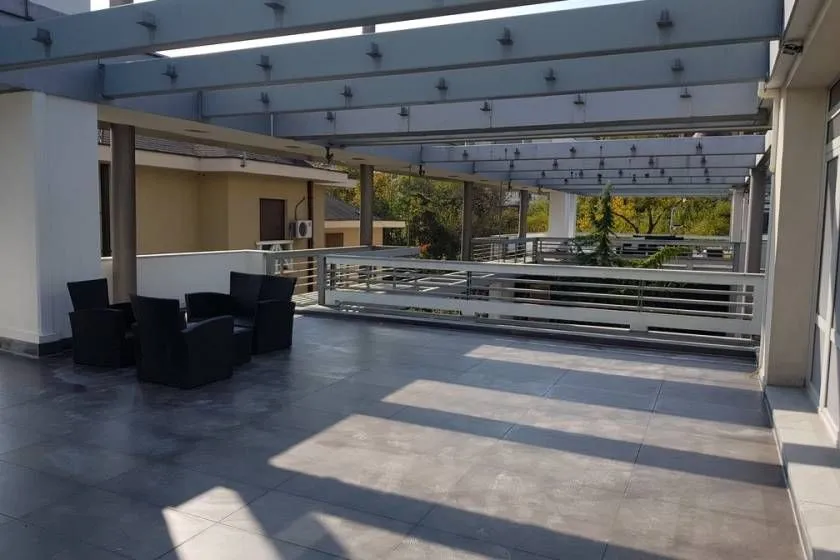 Large terrace with seating furniture and a wooden pergola.