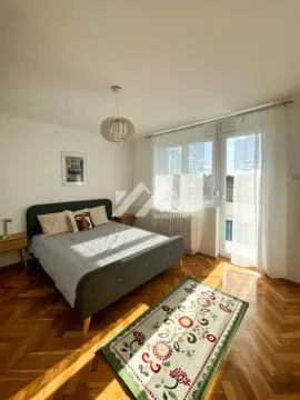 Nameštena spavaća soba sa bračnim krevetom, parketom i izlazom na balkon. - image 5