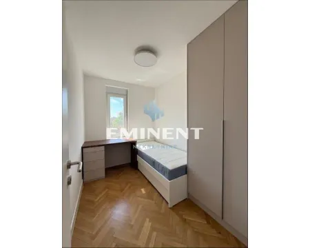 Small bedroom with a bed, wardrobe, desk, and parquet flooring. - image 13