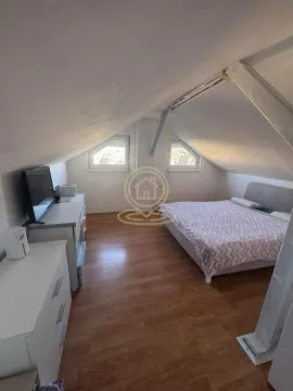 Potkrovna spavaća soba sa bračnim krevetom, komodom i televizorom. - image 6