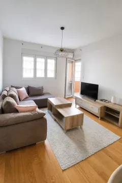 Bright and tidy living room with a sectional sofa, wooden coffee table, and TV. - image 3